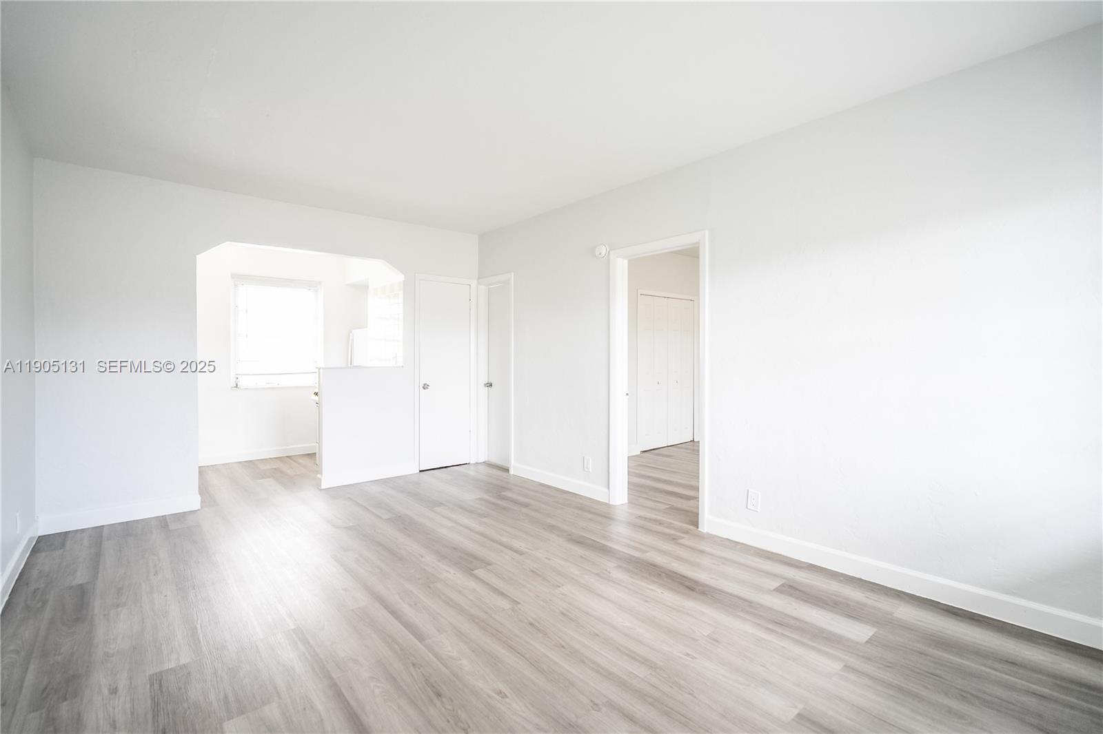 1208 71st Street, Unit 7 Miami Beach, FL 33141 - Photo 3 of 14 an empty room with wooden floor and a window
