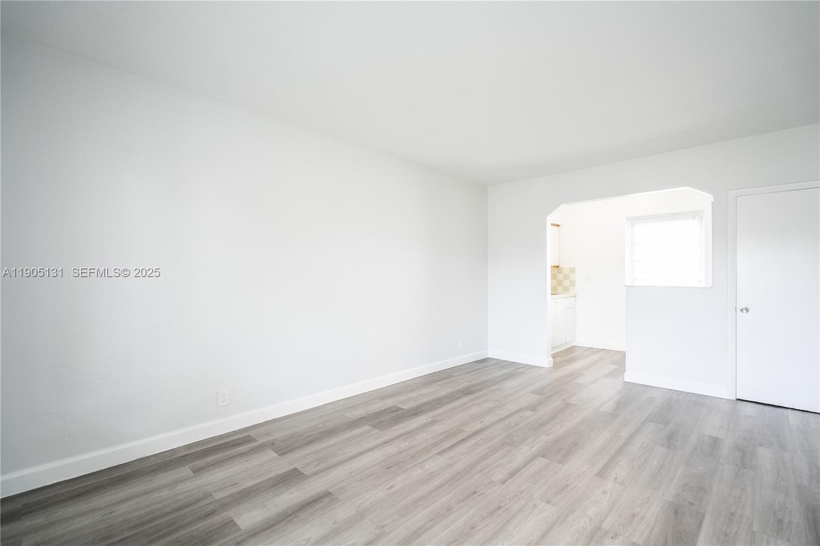 1208 71st Street, Unit 7 Miami Beach, FL 33141 - Photo 4 of 14 an empty room with wooden floor and windows