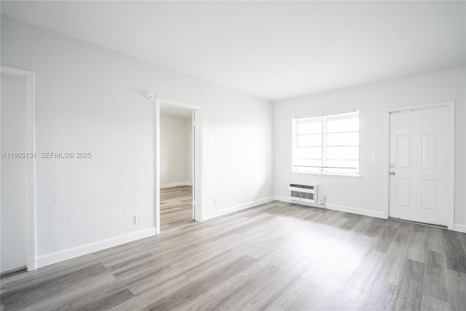 1208 71st Street, Unit 7 Miami Beach, FL 33141 - Photo 5 of 14 an empty room with wooden floor and windows