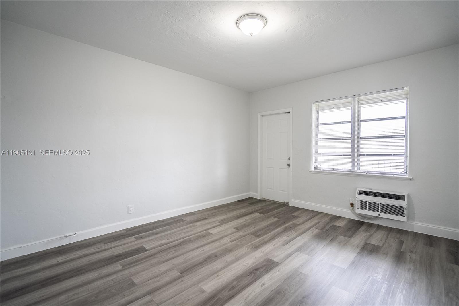 1208 71st Street, Unit 7 Miami Beach, FL 33141 - Photo 7 of 14 an empty room with wooden floor and windows