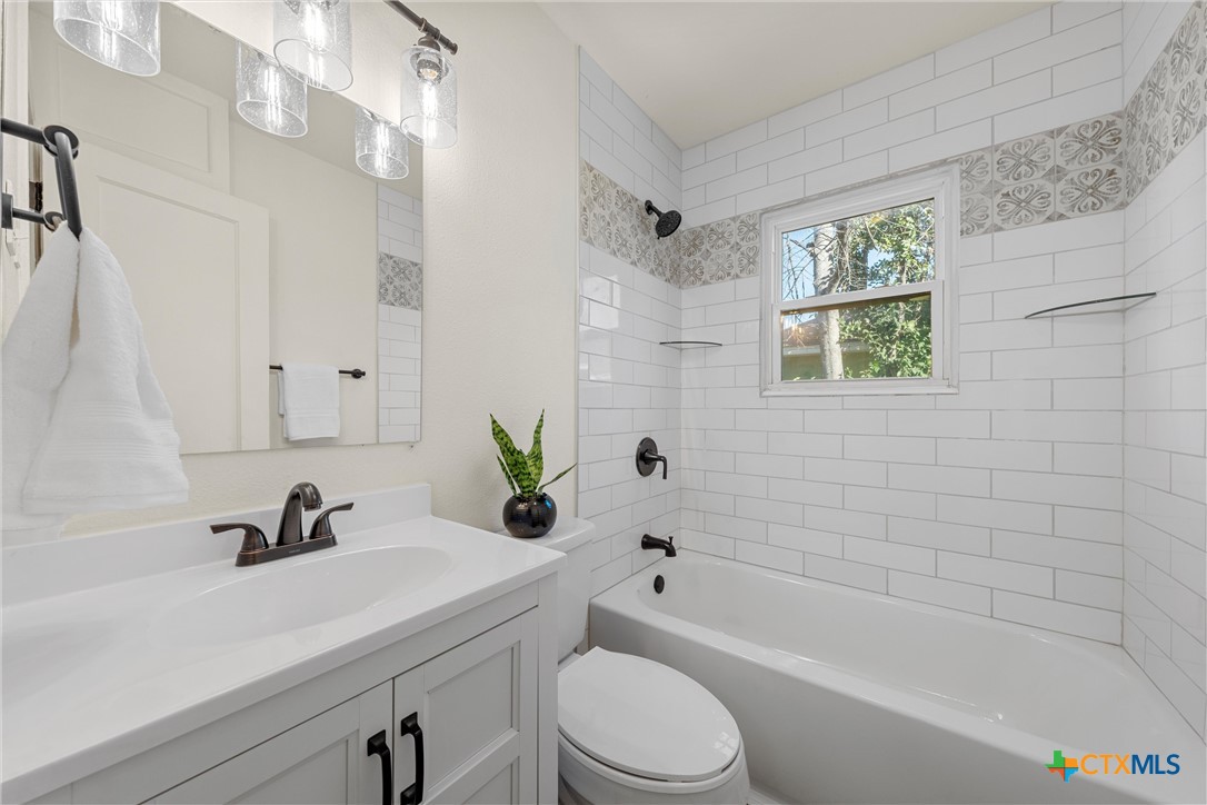 1203 South 5th Street Temple, TX 76504 - Photo 14 of 20 a bathroom with a sink a toilet a window and shower