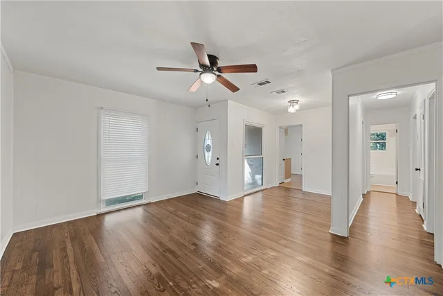 a view of empty room with wooden floor and fan