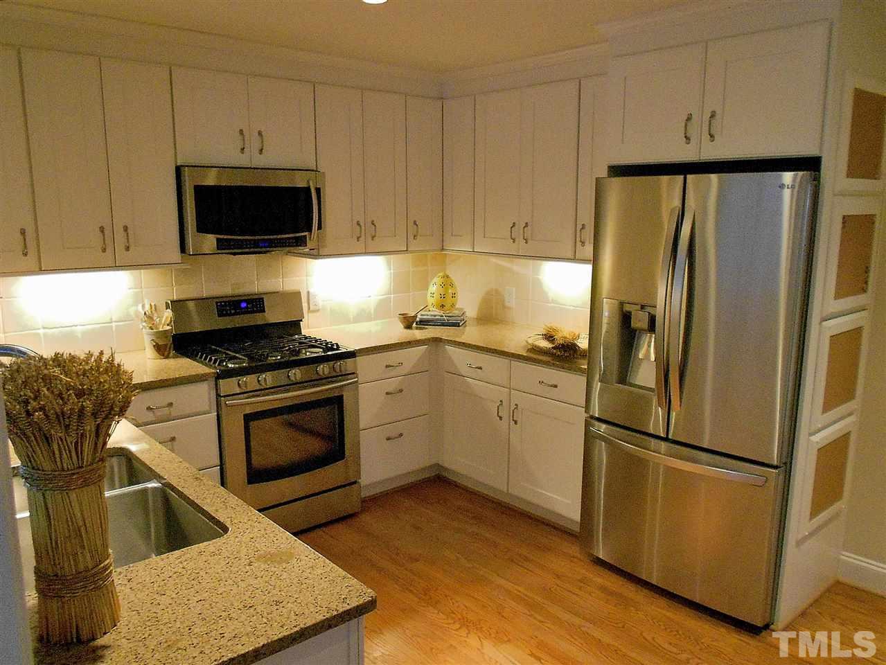 309 Forsyth Street Raleigh, NC 27609 - Photo 7 of 25 a kitchen with stainless steel appliances granite countertop a refrigerator stove and microwave with wooden floor