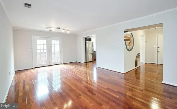 an empty room with wooden floor and windows