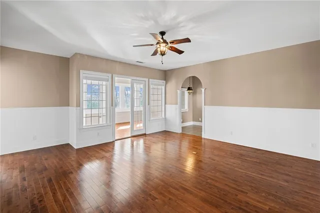 a view of an empty room with a window and wooden floor
