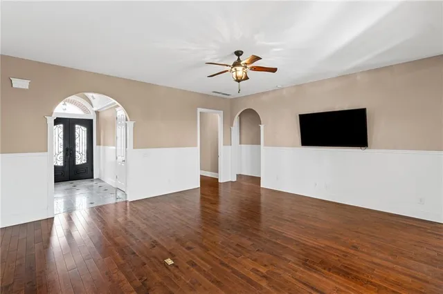 a view of an empty room with wooden floor and a window