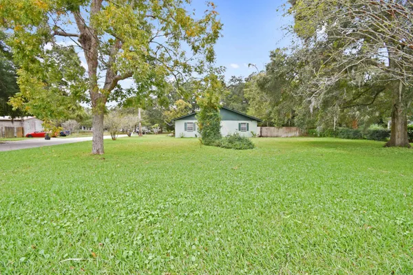 a white house with a big yard and large trees