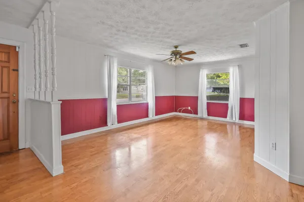 an empty room with windows and chandelier fan