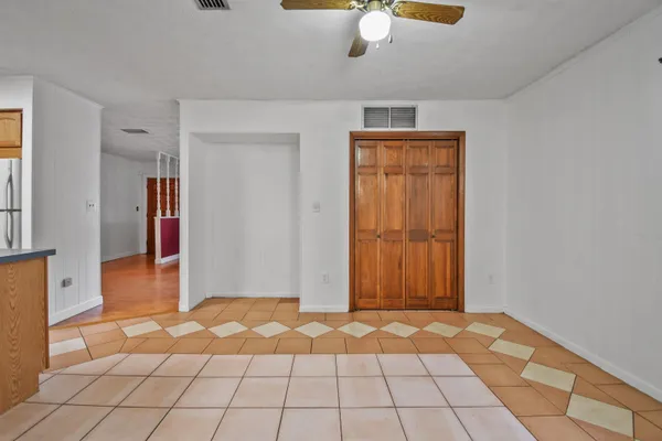 a view of an empty room with window and chandelier fan