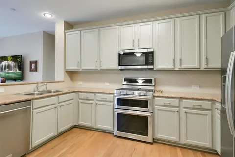 a kitchen with cabinets stainless steel appliances and wooden floor