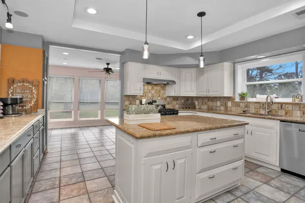 a large kitchen with granite countertop a sink a counter top space appliances and cabinets