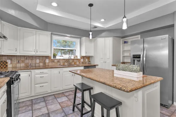 a kitchen with granite countertop white cabinets and refrigerator