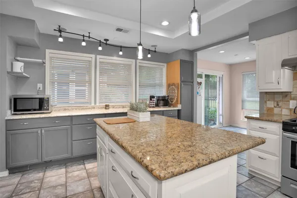 a kitchen with kitchen island granite countertop a stove a sink a center island and a refrigerator