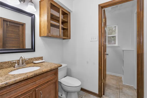 a bathroom with a granite countertop toilet a sink and a mirror