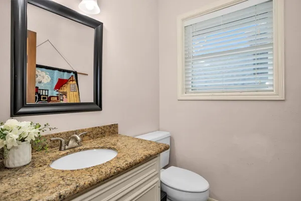 a bathroom with a granite countertop sink mirror vanity and toilet