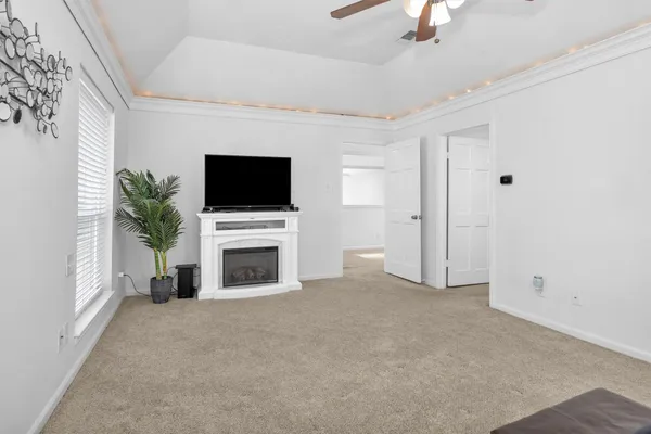 a view of a livingroom with a fireplace a flat screen tv and a ceiling fan
