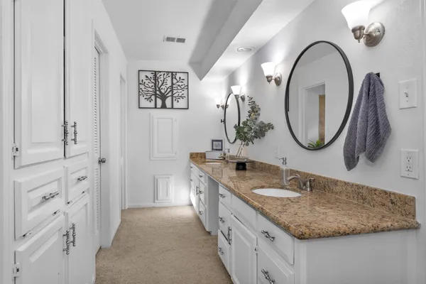 a bathroom with a granite countertop double vanity sink and a mirror
