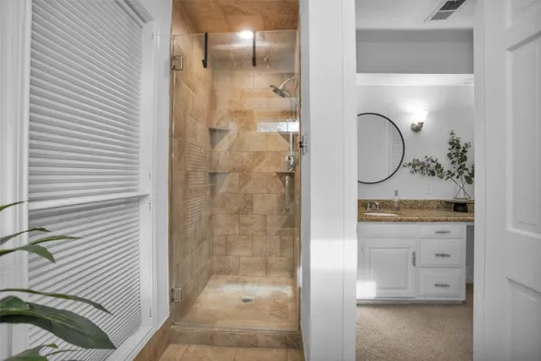 a bathroom with a granite countertop sink a mirror and shower