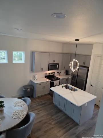 a kitchen with stainless steel appliances a stove a sink and a white wooden cabinets