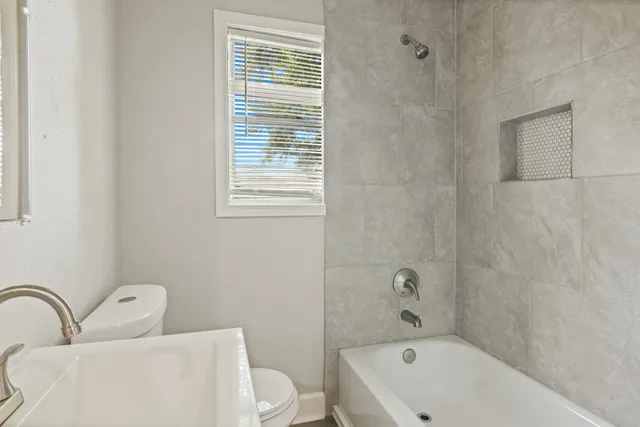 a bathroom with a bathtub sink vanity mirror and toilet