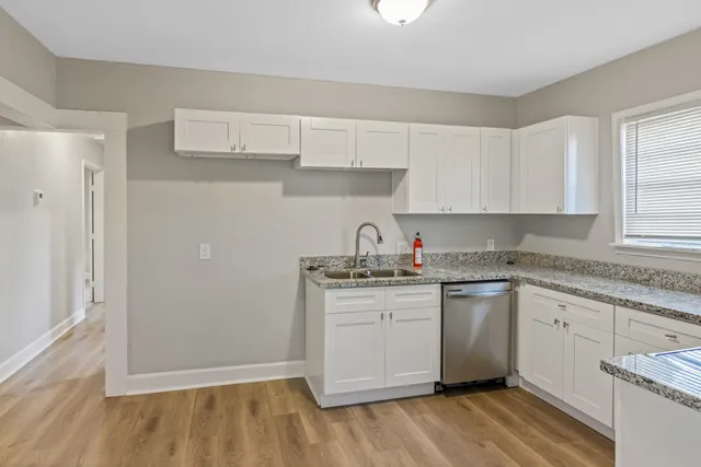 a kitchen with stainless steel appliances granite countertop a sink and cabinets with wooden floor