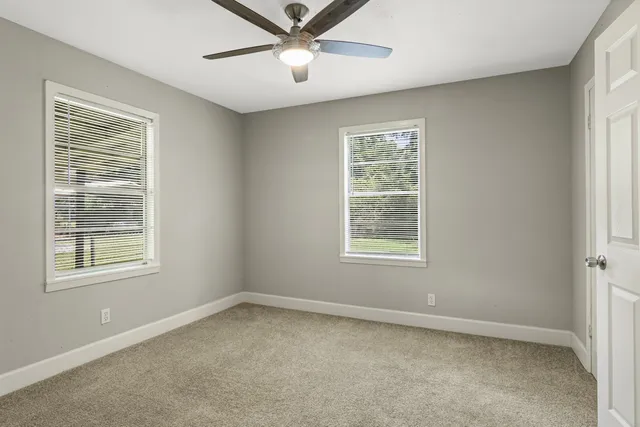 an empty room with a window and a fan