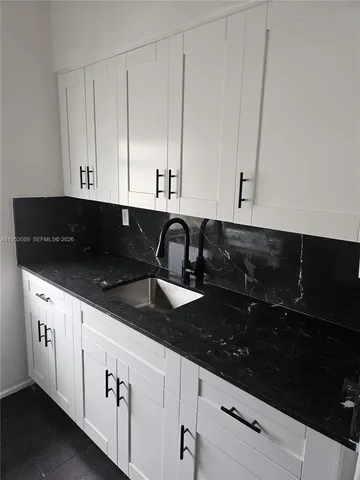 a kitchen with granite countertop white cabinets and black appliances