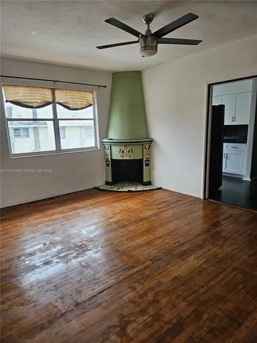 an empty room with wooden floor fireplace and windows