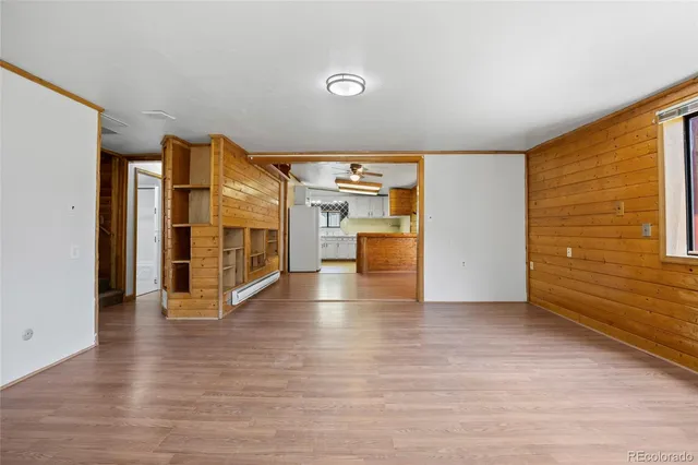 a view of an empty room with a window and wooden floor