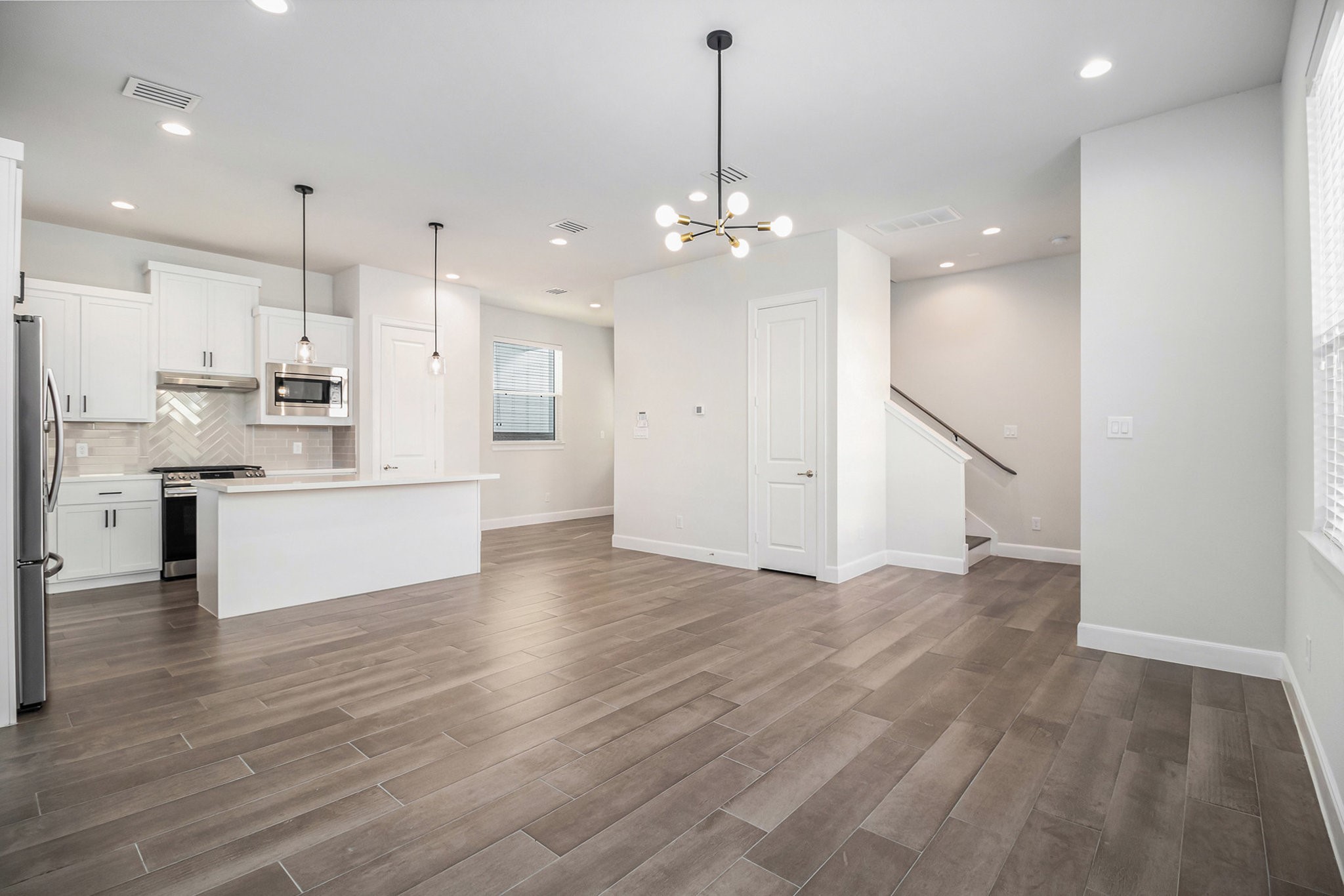 9573 Neuens Road, Unit A Houston, TX 77080 - Photo 4 of 22 a view of a kitchen with granite countertop stainless steel appliances cabinets a wooden floor and a chandelier