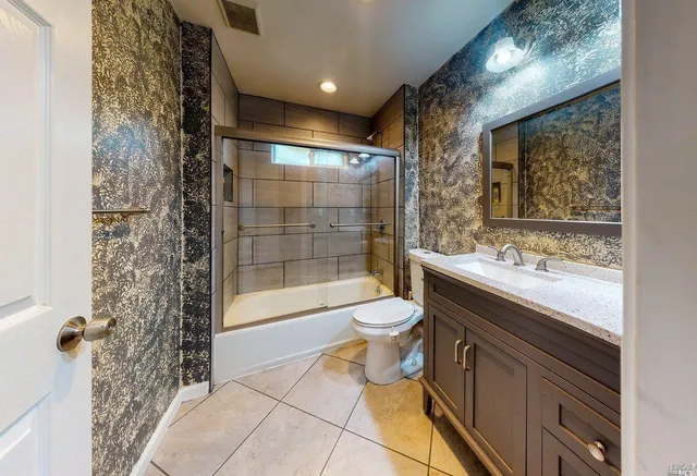 a bathroom with a granite countertop sink a toilet and shower