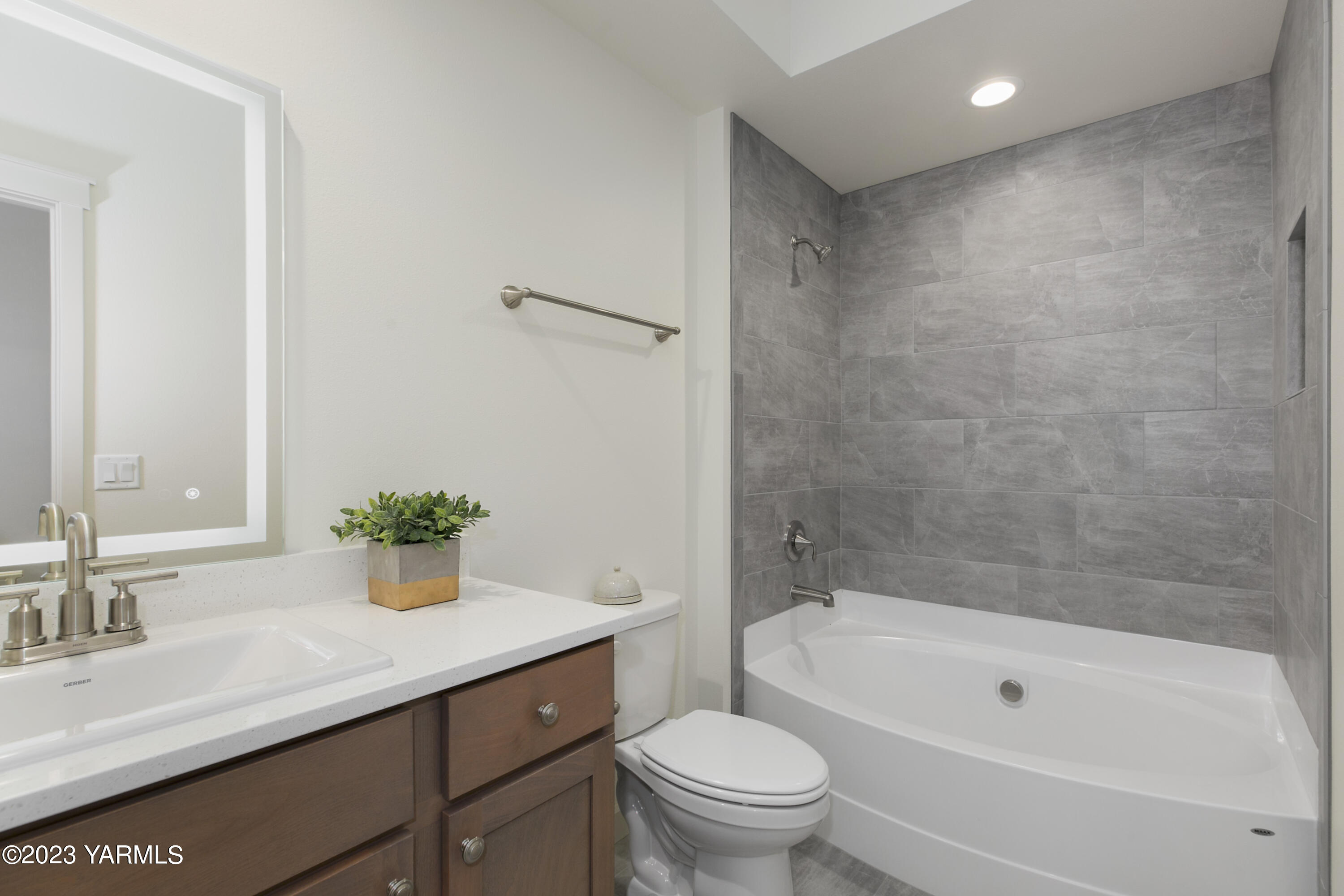 7201 Vista Ridge Avenue Yakima, WA 98903 - Photo 22 of 25 a bathroom with a granite countertop sink a toilet a mirror a bathtub and shower