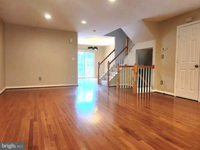 a view of an empty room with wooden floor and stairs