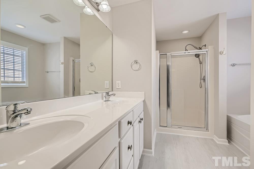 109 Oakbeech Court Holly Springs, NC 27540 - Photo 14 of 28 a bathroom with a double vanity sink a mirror a shower and a bathtub