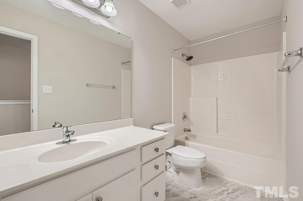 109 Oakbeech Court Holly Springs, NC 27540 - Photo 19 of 28 a bathroom with a toilet a sink a mirror and a shower