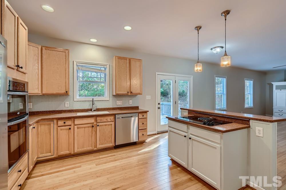 109 Oakbeech Court Holly Springs, NC 27540 - Photo 9 of 28 a kitchen with stainless steel appliances granite countertop a stove a sink and white cabinets with wooden floor