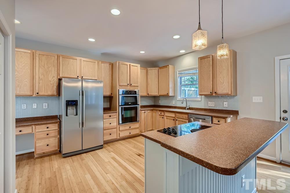 109 Oakbeech Court Holly Springs, NC 27540 - Photo 10 of 28 a kitchen with stainless steel appliances granite countertop a refrigerator a sink dishwasher a stove and white countertops with wooden floor