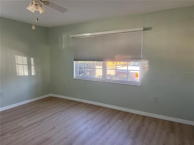 a view of an empty room with wooden floor and a window