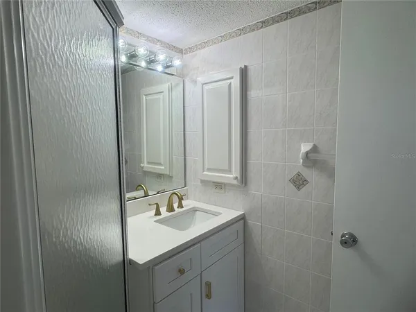 a bathroom with a shower sink vanity and mirror
