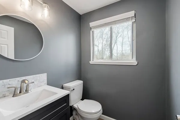 a bathroom with a toilet sink vanity and mirror