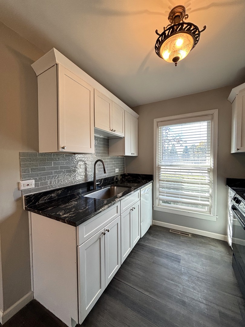 991 Spring Road Elmhurst, IL 60126 - Photo 4 of 17 a kitchen with stainless steel appliances granite countertop a sink stove and white cabinets with wooden floor