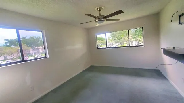 an empty room with windows and fan view