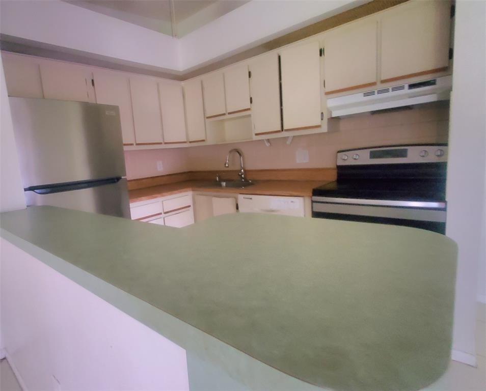9731 West McNab Road, Unit 208 Fort Lauderdale, FL 33321 - Photo 7 of 31 a kitchen with a refrigerator and white cabinets