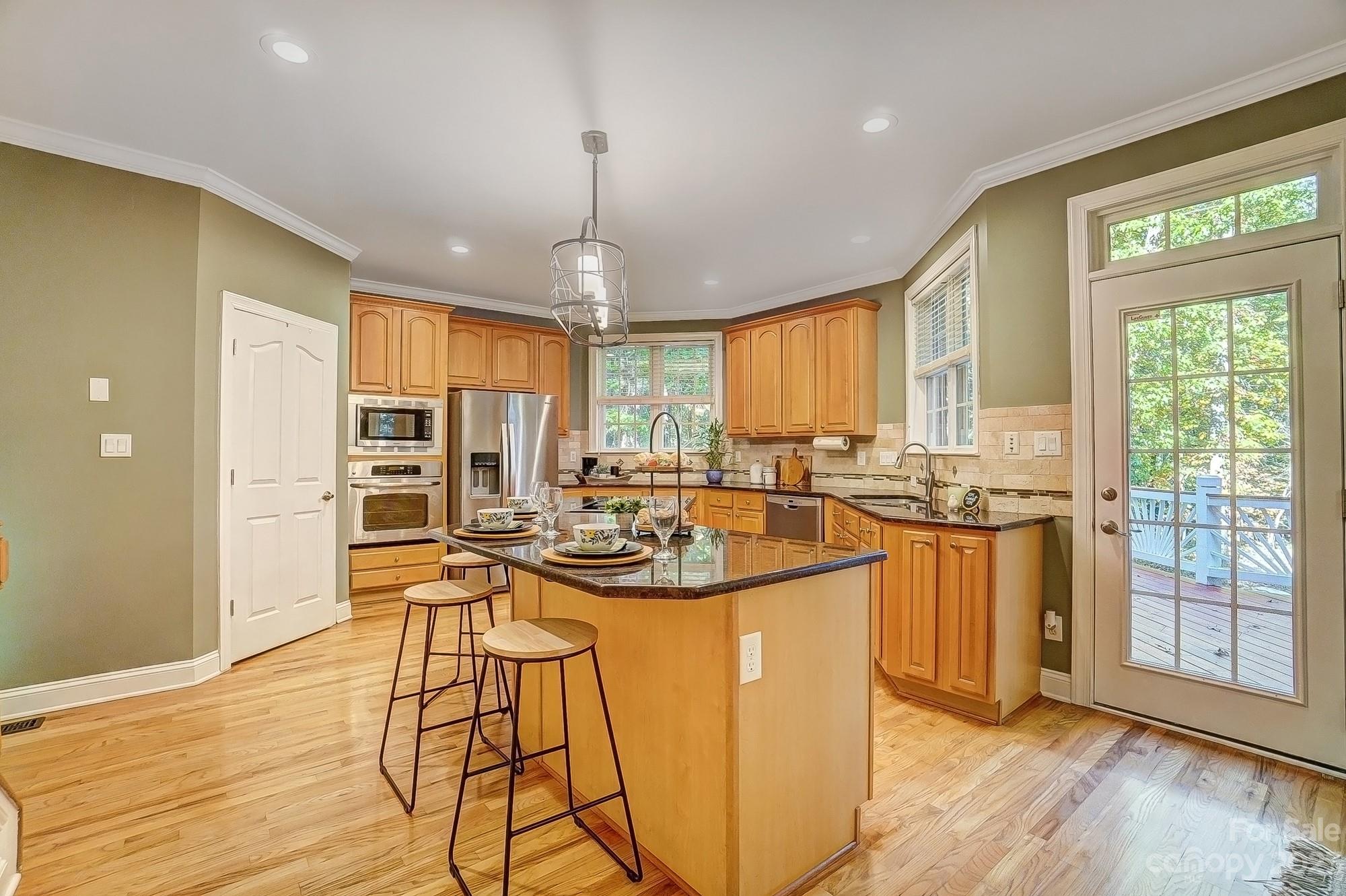 9710 Shadowmere Lane Weddington, NC 28104 - Photo 15 of 46 a view of a kitchen with kitchen island granite countertop wooden floors granite counter tops and a window