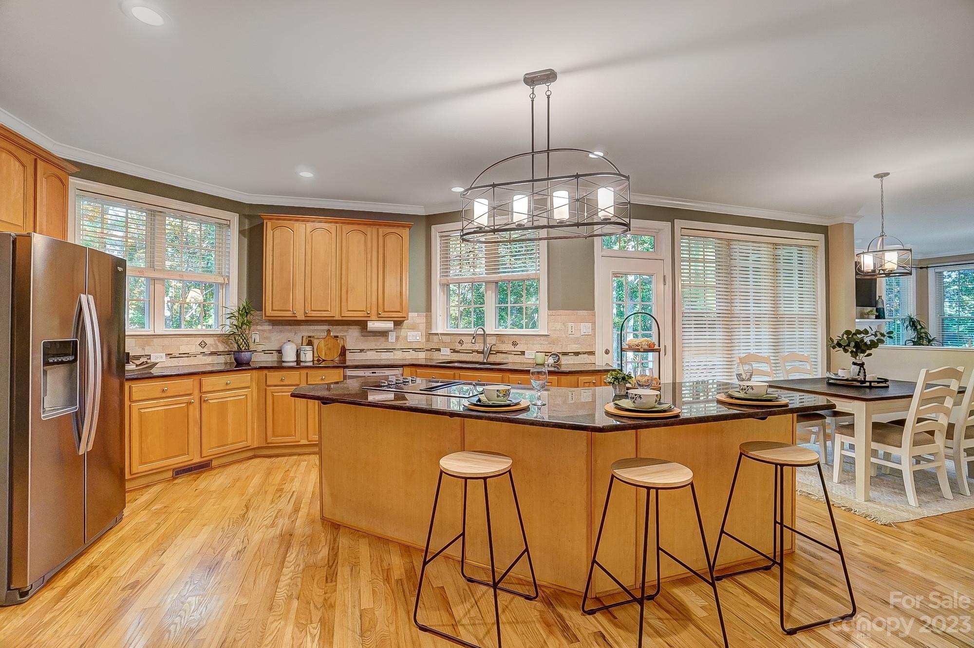 9710 Shadowmere Lane Weddington, NC 28104 - Photo 16 of 46 a kitchen with stainless steel appliances granite countertop a stove a refrigerator a sink a dining table and chairs with wooden floor