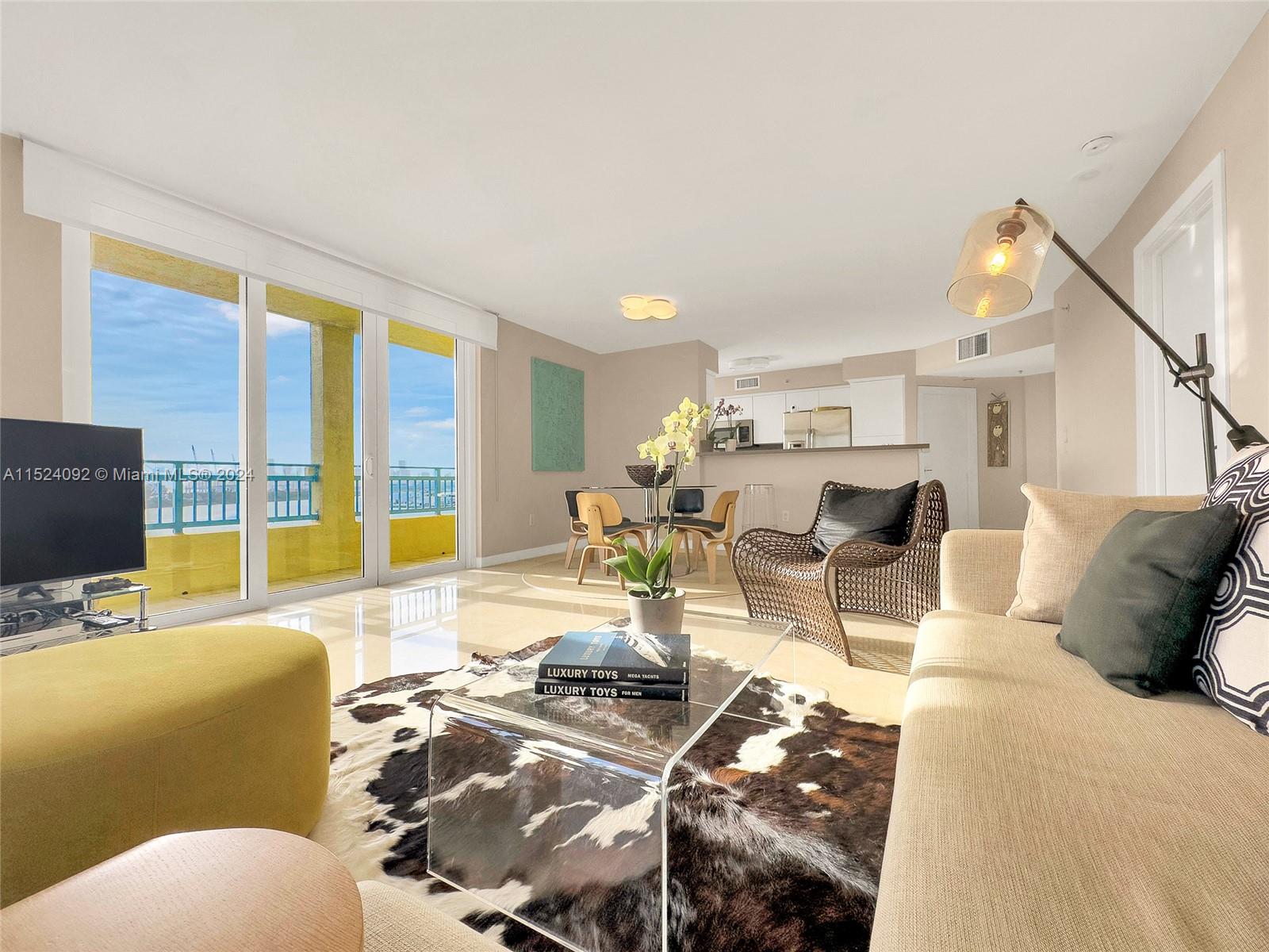 90 Alton Road, Unit 902 Miami Beach, FL 33139 - Photo 2 of 35 a living room with furniture floor to ceiling window and a flat screen tv