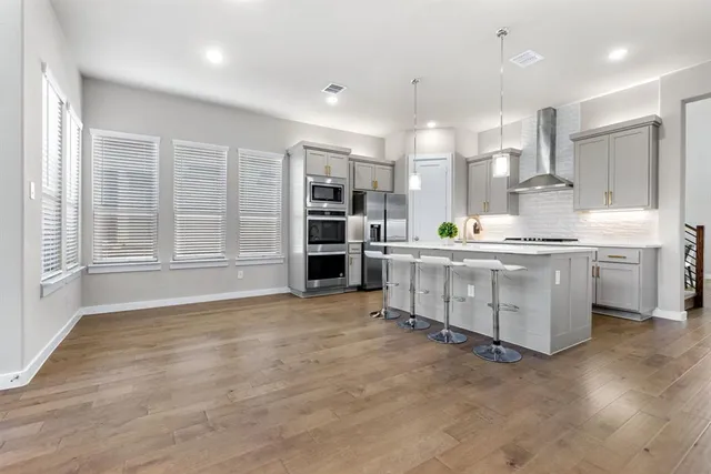 a kitchen with stainless steel appliances a sink a stove a refrigerator cabinets and a large window