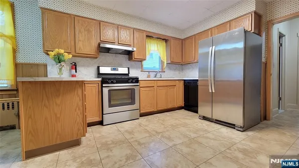 a kitchen with stainless steel appliances granite countertop a refrigerator a stove a sink and a window
