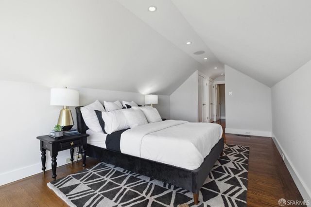 a spacious bedroom with a bed and wooden floor