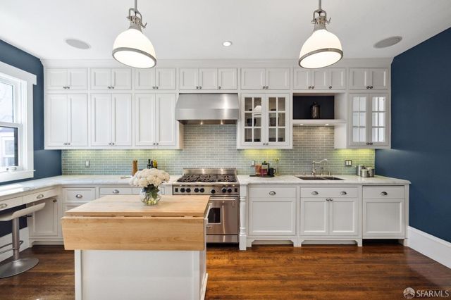 a kitchen with kitchen island granite countertop a sink a stove and cabinets